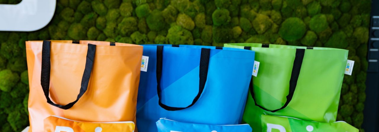Orange, blaue und grüne Shopper und Kulturbeutel aus gebrauchten NXP-Messebannern