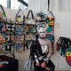 Person in schwarz-weißem Kostüm vor einer Wand mit bunten Upcycling-Taschen von PrideHEROES.