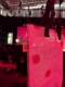 Einkaufstasche aus einem EXPO REAL-Mesh-Banner mit großen Punkten und schwarzen Henkeln in einer pink beleuchteten Veranstaltungshalle